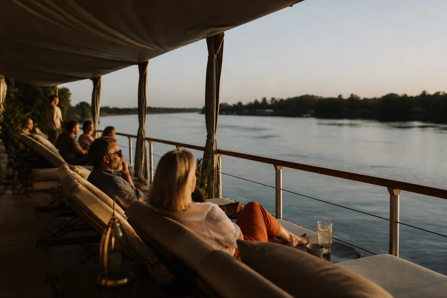 Nile cruise ship sailing past Luxor temple ruins at sunset